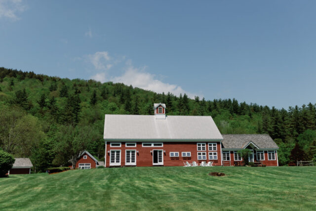 Summer wedding venue building with green lawn and wooded hills