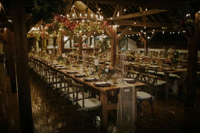 Elegant farm wedding dinner tables with greenery and warm lights